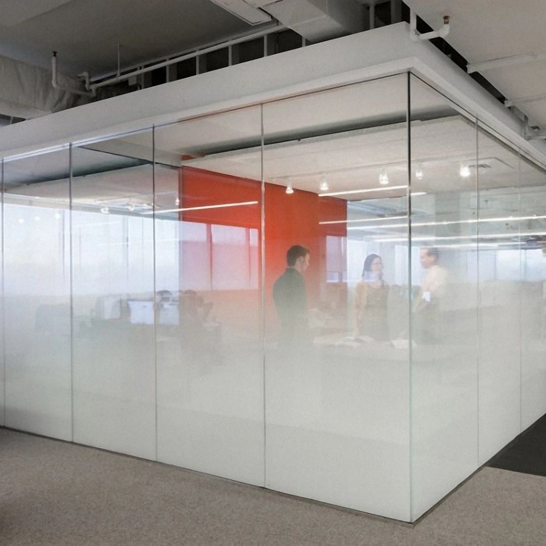 Modern office with frosted glass meeting room and people inside.