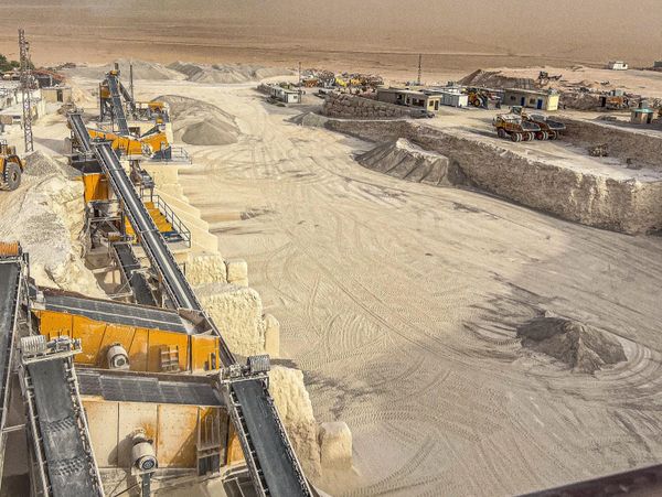 A large sand quarry with conveyor belts and machinery in a desert.