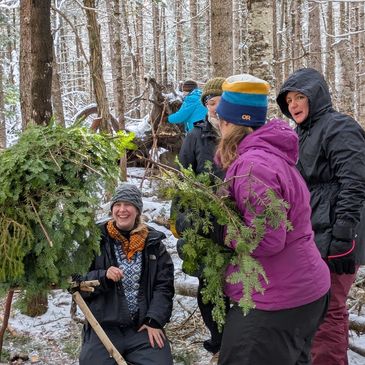 Group collecting evergreen branches in snowy forest.