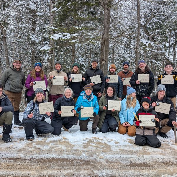 Group photo of people holding certificates in a snowy forest.