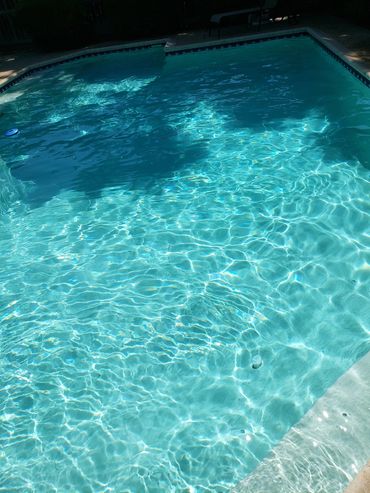 Sunlit swimming pool with clear blue water and gentle ripples.