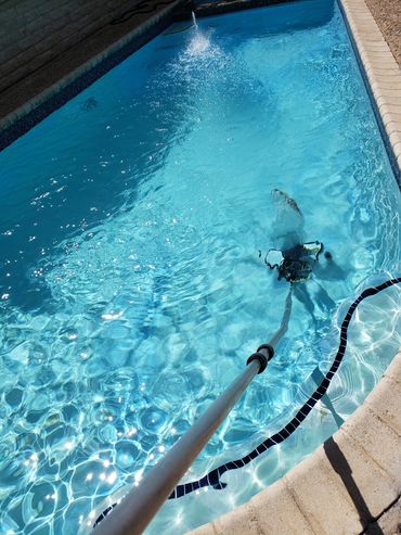 A pool cleaner vacuuming the bottom of a clear swimming pool.