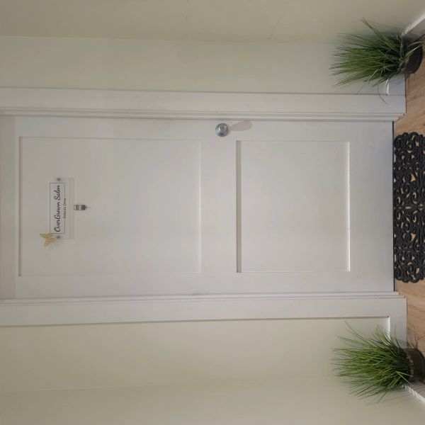 White door with a sign and plants on both sides.