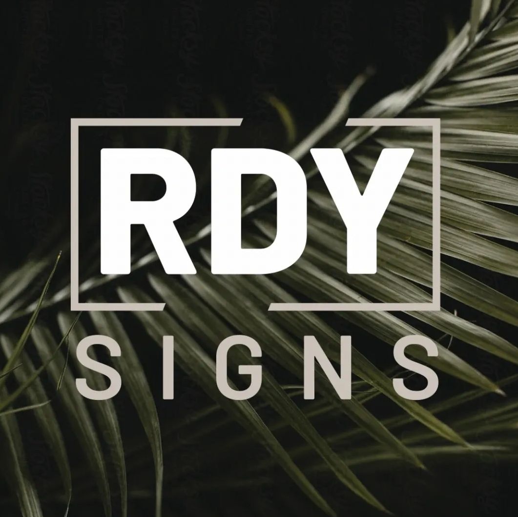 Logo for RDY Signs with a natural background of green leaves.