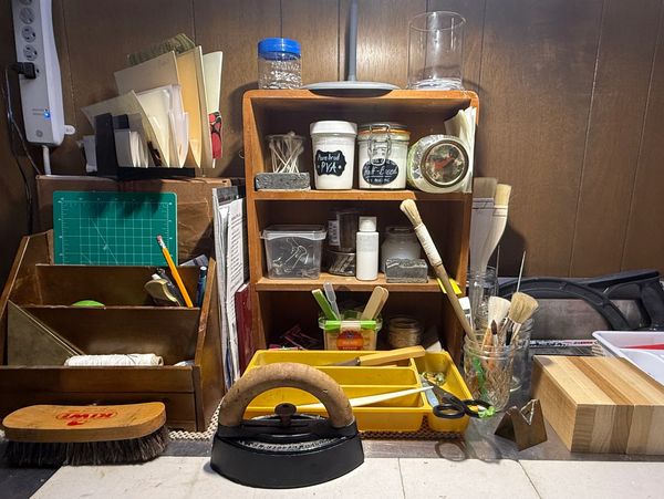 Organized workspace with art supplies, brushes, and vintage iron.