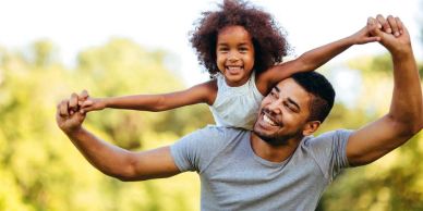 Father giving his daughter a piggyback ride outdoors.