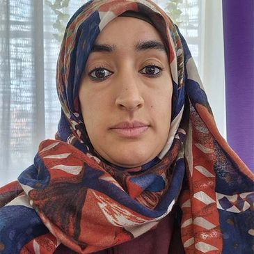 Close-up of a woman wearing a colorful patterned hijab indoors.