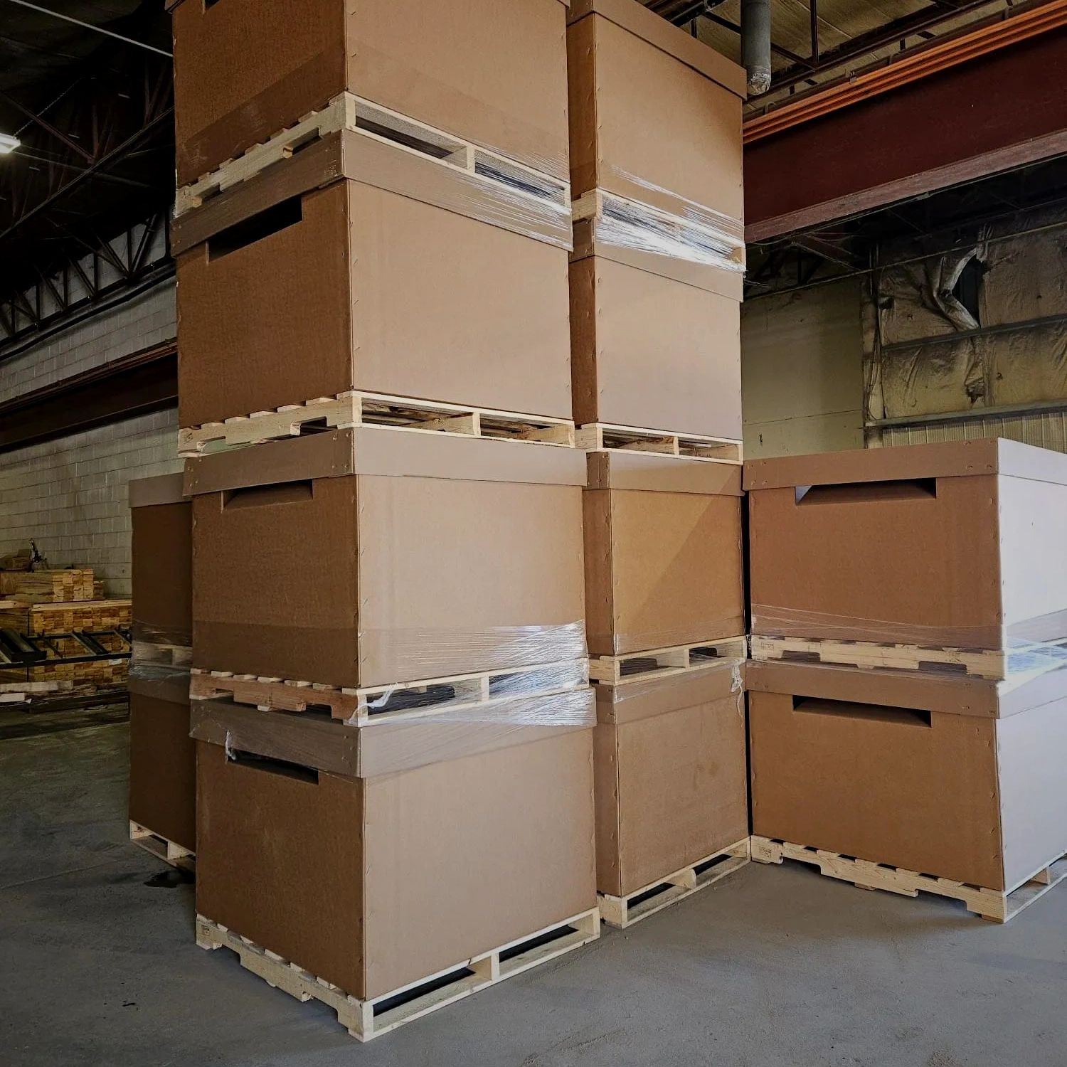 Large cardboard shipping boxes stacked on wooden pallets inside a warehouse.