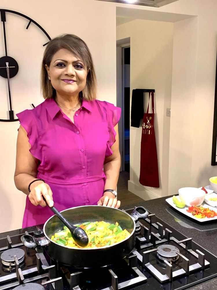 A picture of Anita cooking in her kitchen wearing a pink dress.