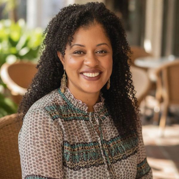 Smiling woman with curly hair sitting indoors.
