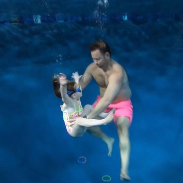 A man holding a girl in the swimming pool
