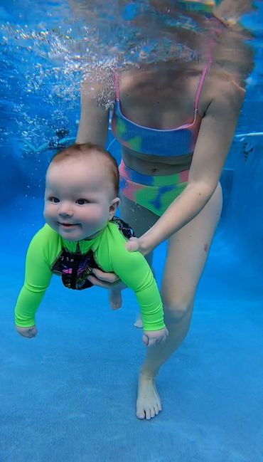 A baby swimming with a female.