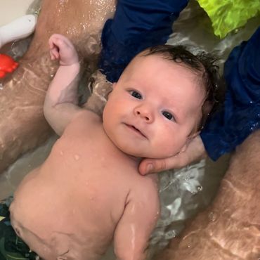 A baby taking a bath in the bathing tub.