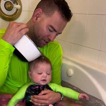 A man giving a bath to a baby.