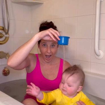 A woman pouring some water on the baby.