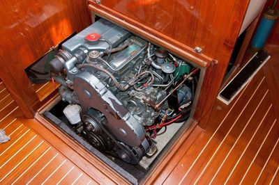 Boat engine installed in a wooden compartment with polished floor.