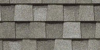 Close-up of gray asphalt roof shingles in a staggered pattern.
