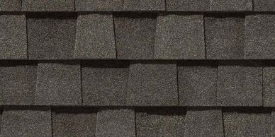 Close-up of dark asphalt roof shingles arranged in overlapping rows.