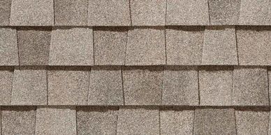 Close-up of overlapping gray roof shingles arranged in neat rows.