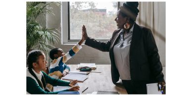Teacher giving a high-five to a student in a classroom.