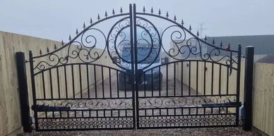 Decorative black wrought iron gate with intricate scrollwork and circular design.