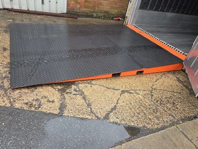 Orange and black metal ramp on cracked ground outside a building.