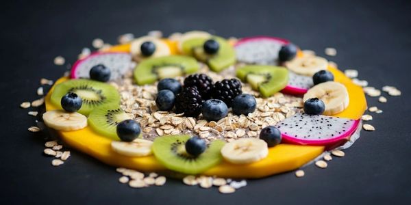 A colorful fruit and oats arrangement on a dark surface.