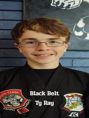 Young martial artist Ty Ray in black belt uniform with Kenpo patches.
