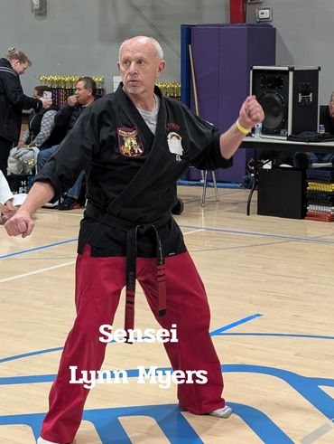 Sensei Lynn Myers demonstrating a martial arts stance in a gym.