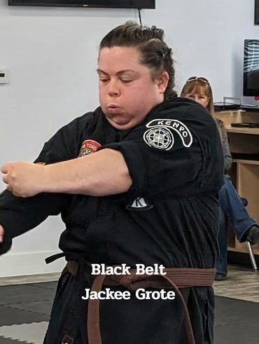 Martial artist in black uniform practicing Kenpo with focused expression.