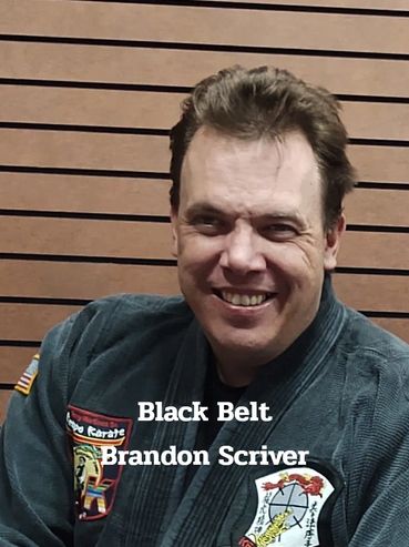 Brandon Scriver smiling in his martial arts black belt uniform.