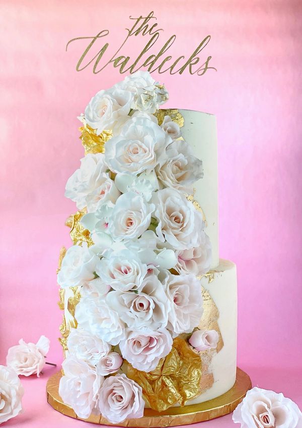 White wedding cake gilded in gold foil with lush silk roses.