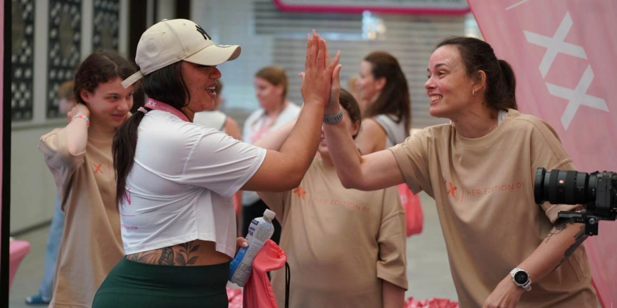 Two women happily high-fiving each other during a casual event.