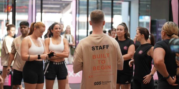 Group of people in a gym setting, with staff member leading the session.