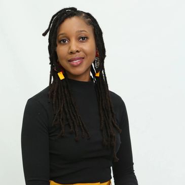 Woman with long braided hair and colorful earrings.