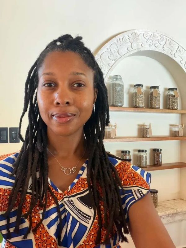 Mujer con rastas y blusa colorida sonriendo.
