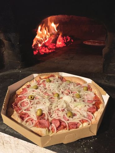 pizza artesanal de calabresa com cebola no forno a lenha