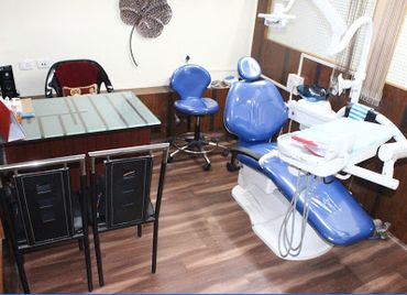 A modern dental clinic room with a dental chair and desk.