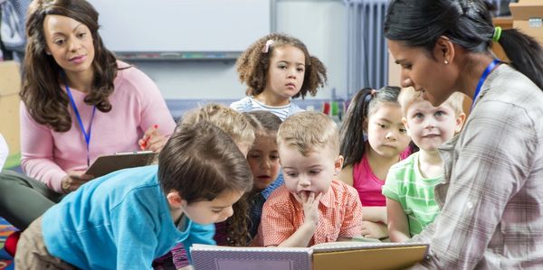 Woman showing a book to children