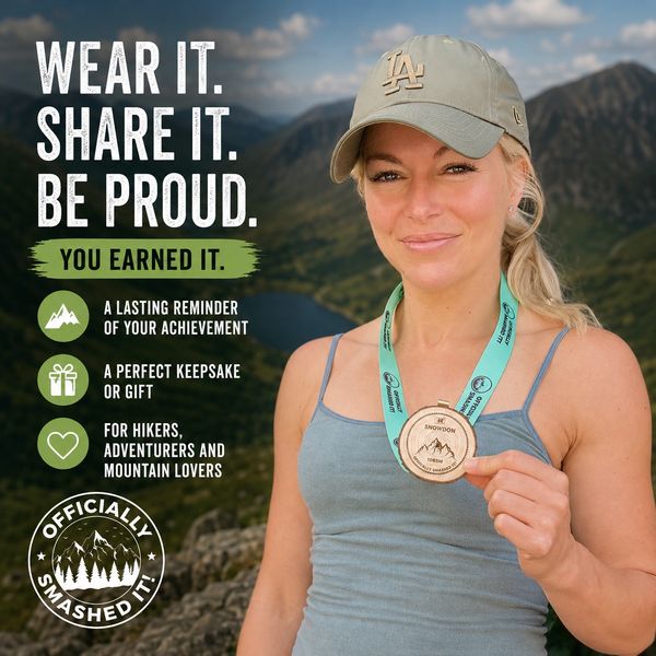Woman proudly displays a hiking achievement medal with a mountain backdrop.