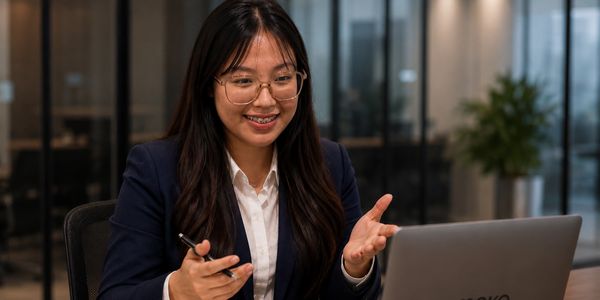 A woman in business attire engaging in a video call on her laptop.
