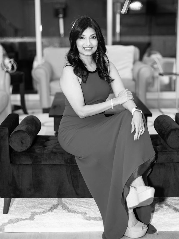 Woman in elegant dress sitting on a bench, smiling.