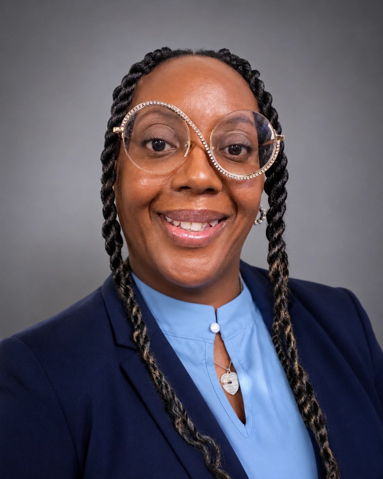 Woman with braided hair and unique glasses smiling.
