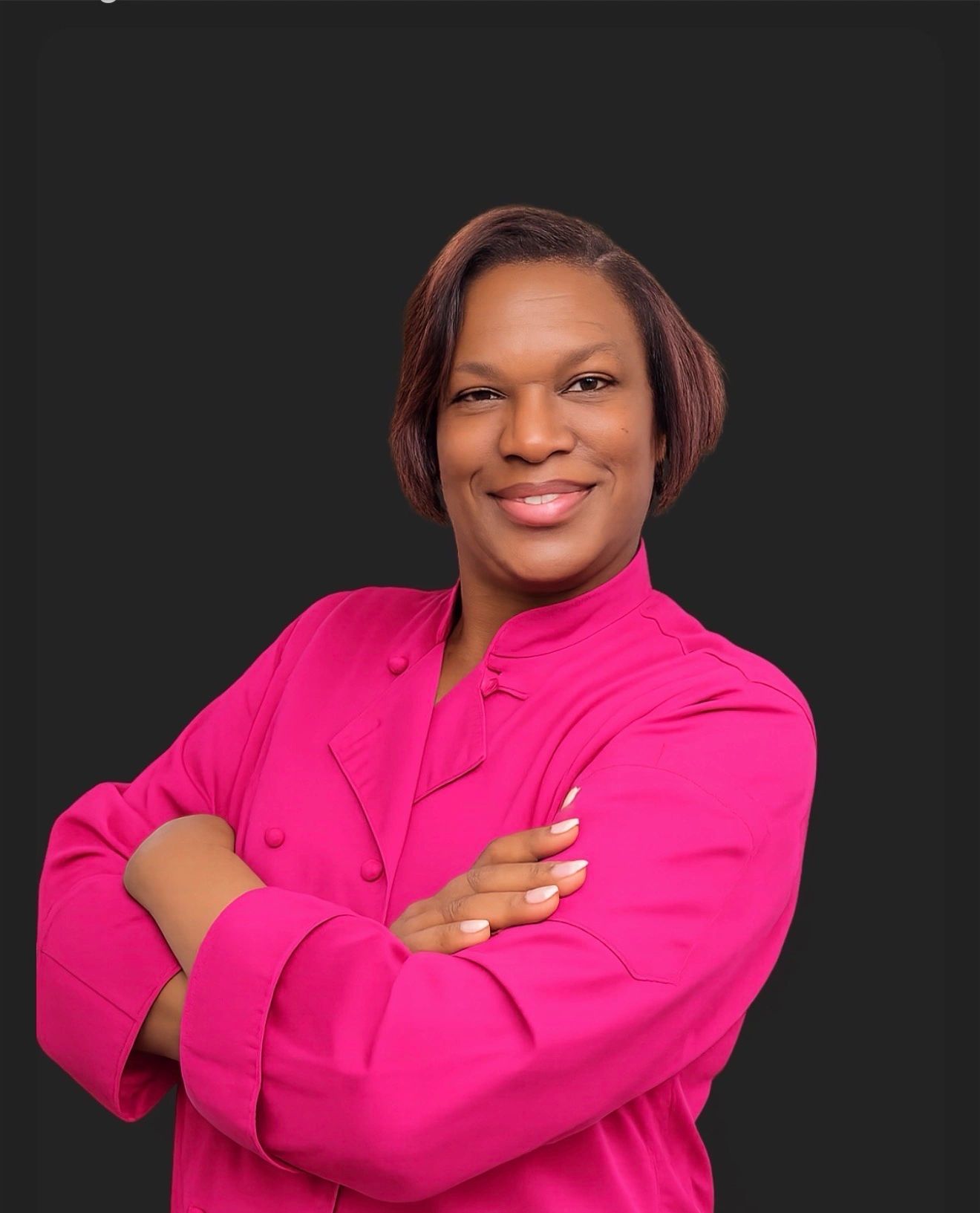 Confident woman in a bright pink chef coat.
