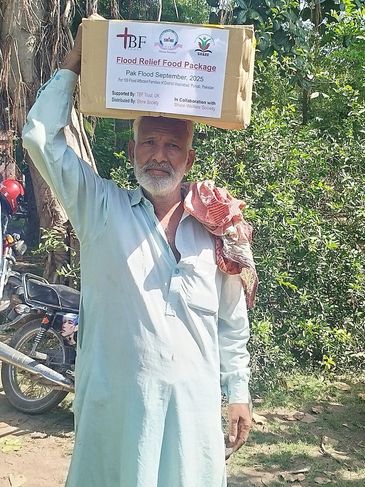 Man holding a flood relief food package on his head outdoors.