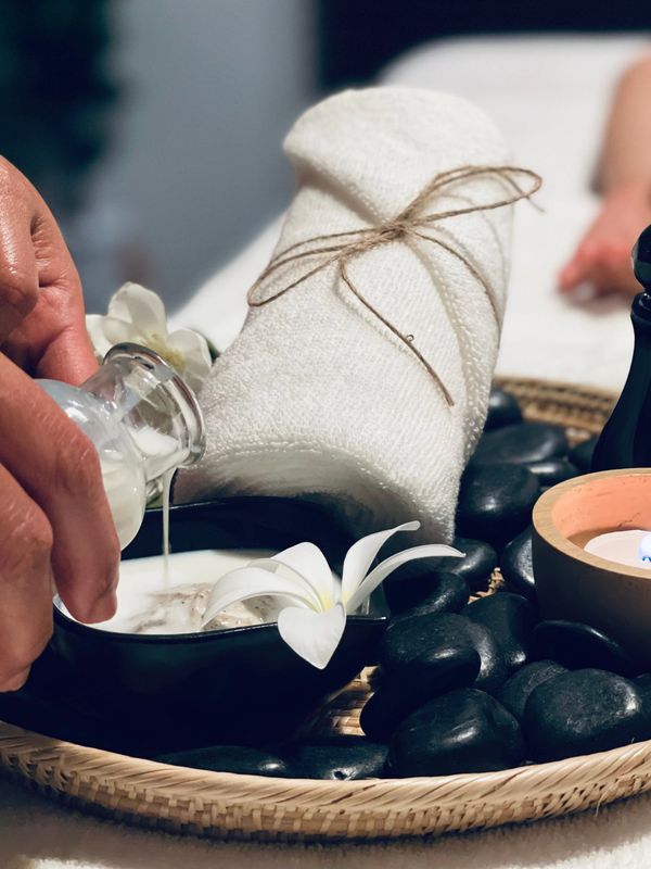 Spa setup with towel, stones, flowers, and massage oil.