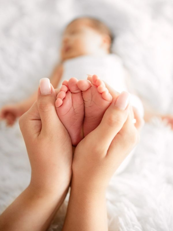 Adult hands holding tiny baby feet gently.
