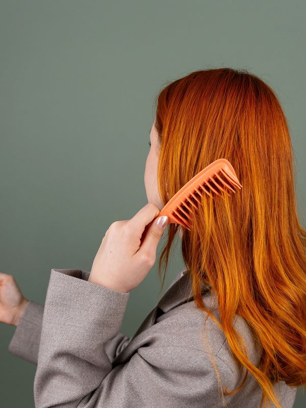 Woman combing her vibrant red hair.