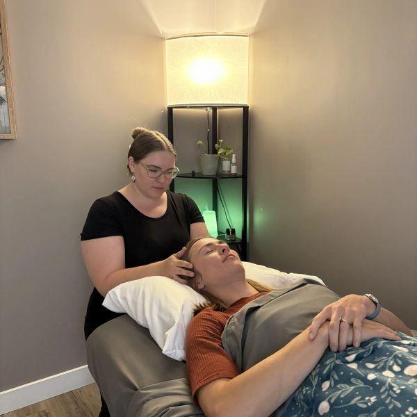 Therapist giving head massage to relaxed client.