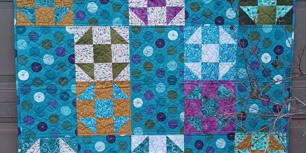 Colorful patchwork quilt with geometric patterns and polka dot fabrics.